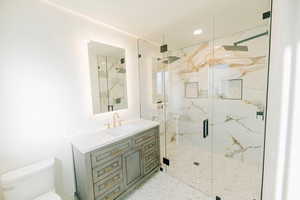 Bathroom with a marble finish shower, vanity, and recessed lighting