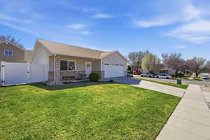 View of front facade with a gate, driveway, brick siding, a garage, and roof with shingles