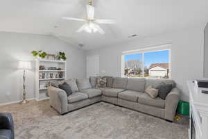 Carpeted living room with a ceiling fan and baseboards
