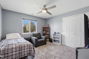 Carpeted bedroom featuring ceiling fan and a closet