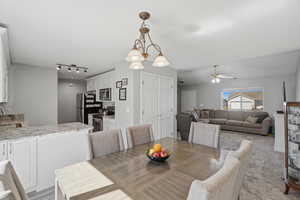 Dining room with suspended lighting, a ceiling fan, and light colored carpet