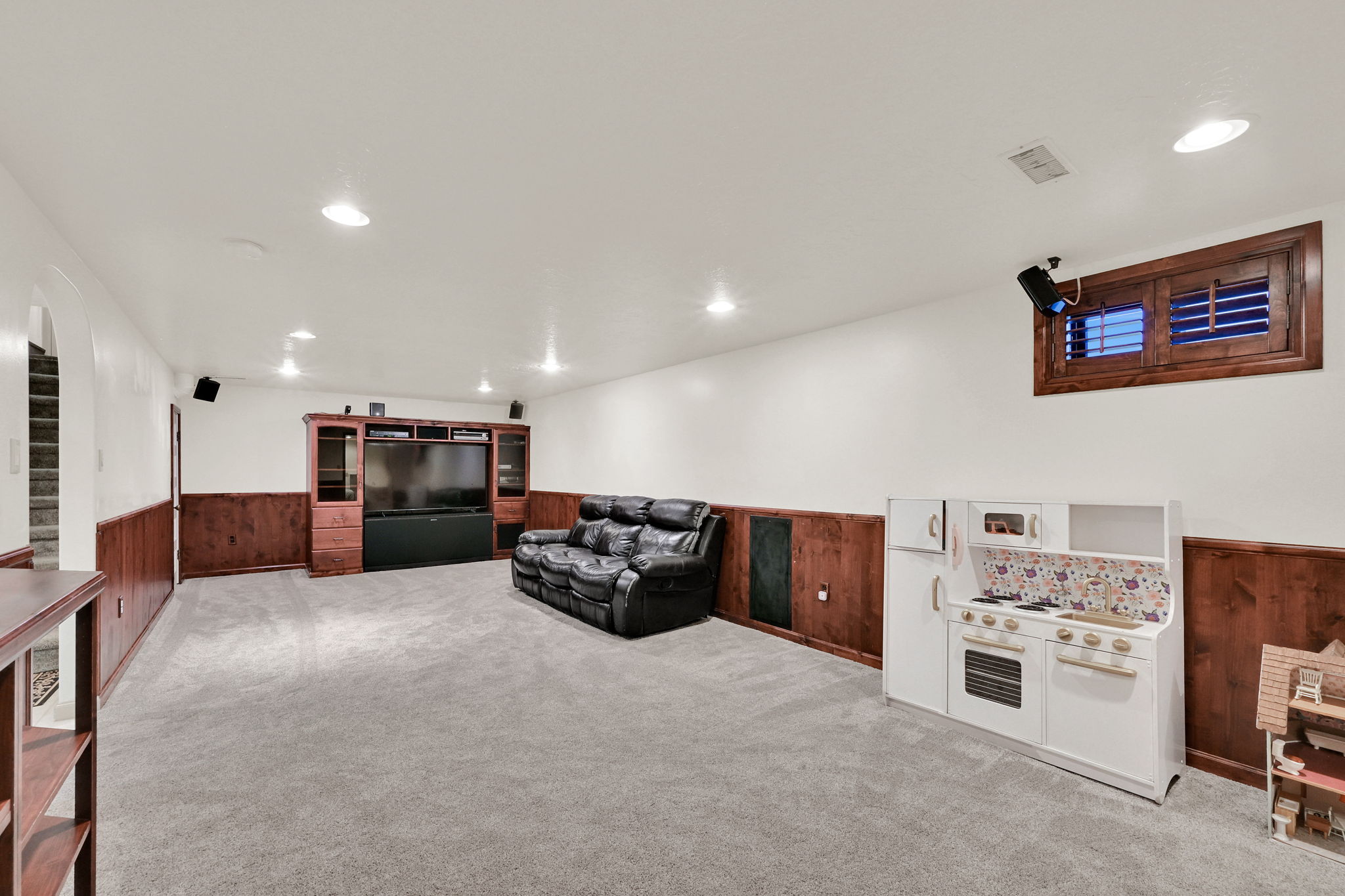 Living room with wainscoted walls, light carpet, built ins, and recessed lighting
