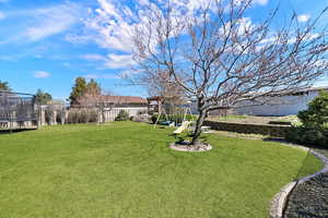 Fenced backyard featuring a trampoline and a playground