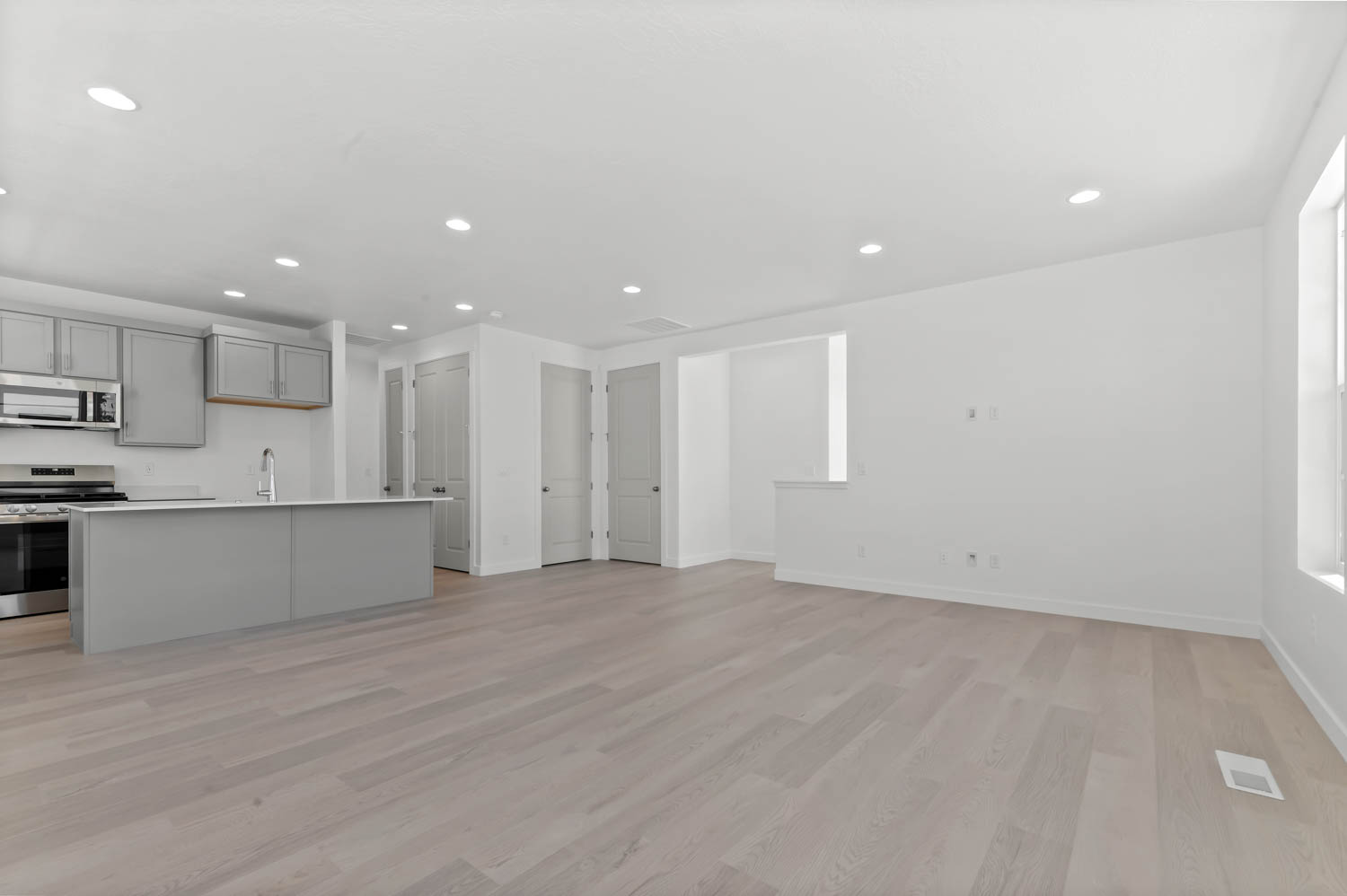 Kitchen with stainless steel appliances, recessed lighting, gray cabinets, light wood-style flooring, and light countertops