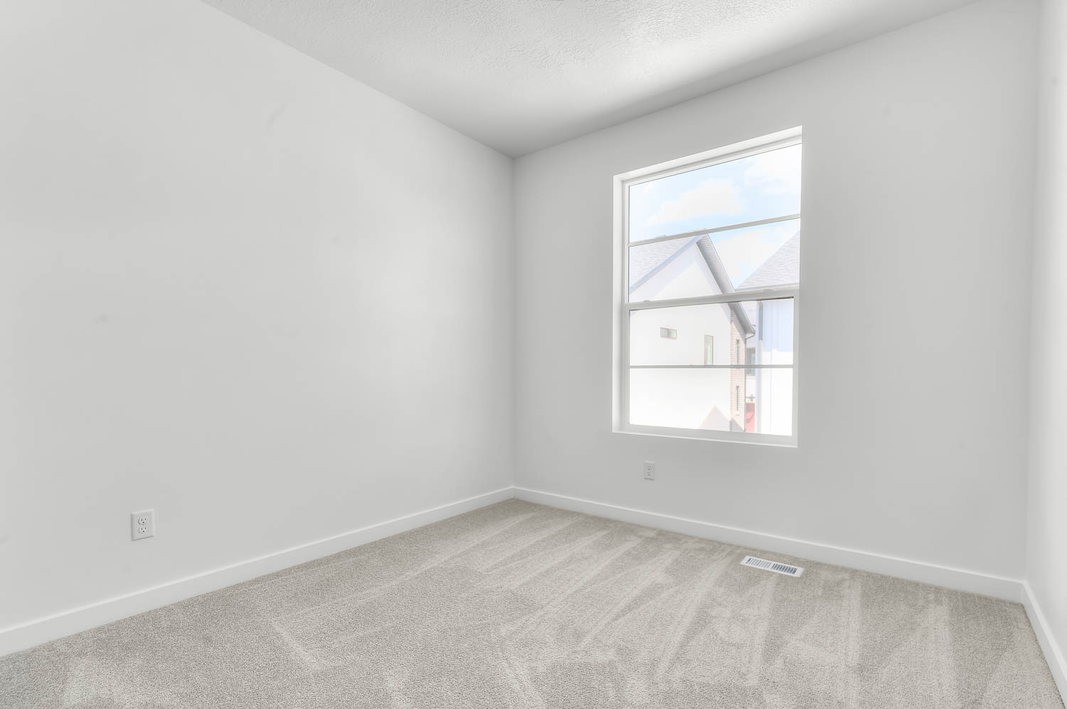 Empty room with light colored carpet and a textured ceiling