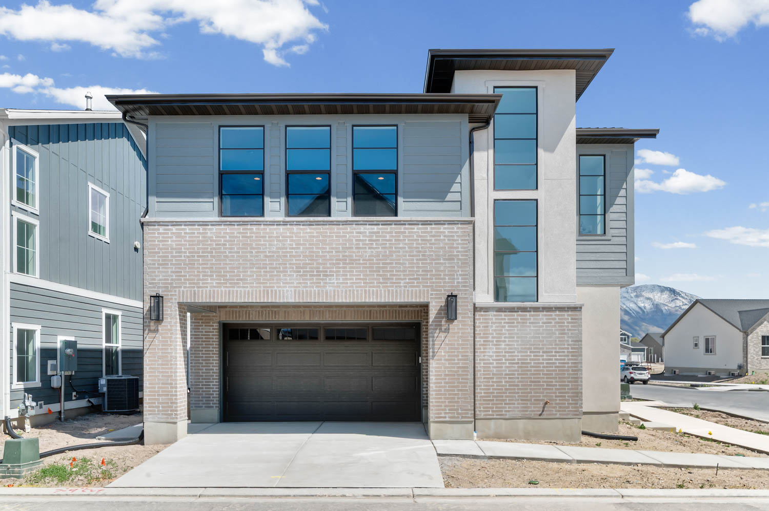 Contemporary house featuring a garage, concrete driveway, brick siding, and a mountain view
