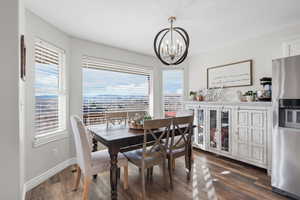 Dining area with dark wood-style floors and hanging lights