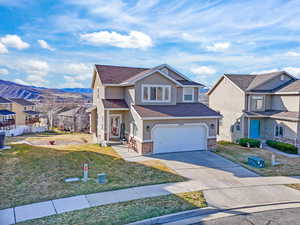 Traditional home with stucco siding, concrete driveway, a residential view, an attached garage, and a front yard