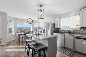 Kitchen with a breakfast bar area, dark wood finished floors, stainless steel appliances, a center island, and gray cabinets