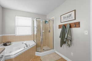 Bathroom featuring a shower stall, a jetted tub, and light tile patterned flooring