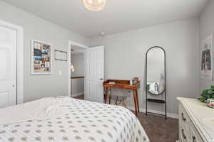 Bedroom with baseboards and dark carpet