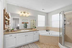 Full bathroom featuring a shower stall, vanity, a garden tub, and light tile patterned floors