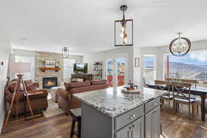 Kitchen featuring light stone counters, dark wood-style flooring, a center island, and a chandelier