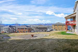 View of grassy yard with a mountain view, a residential view, and a balcony