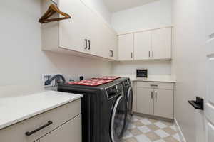 Laundry room featuring light flooring, washer and dryer, and cabinet space