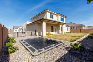 Back of house featuring a patio area, stucco siding, a fenced backyard, a trampoline, and a residential view