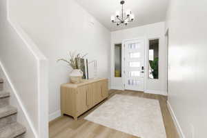 Entryway featuring light wood-style floors and a chandelier