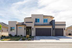 Contemporary home with driveway, stucco siding, a garage, and an attached garage