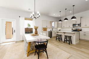 Dining room with suspended lighting and light wood finished floors