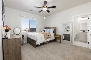 Bedroom featuring light colored carpet, a ceiling fan, and connected bathroom