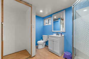 Full bathroom featuring vanity, light wood-style flooring, a shower stall, and recessed lighting