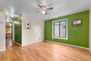 Empty room with a ceiling fan and light wood-style floors