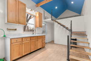 Kitchen featuring light countertops, light wood-type flooring, light wood finish cabinetry, and lofted ceiling