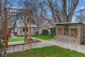 View of yard with a patio area, a pergola, and an outdoor structure
