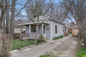 Shotgun-style home with a fenced front yard, a gate, and covered porch