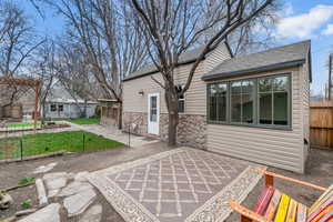 View of front of home with a shingled roof, stone siding, and a patio area