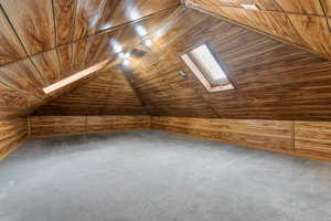 Additional living space with a vaulted wooden ceiling, carpet flooring, and wood walls