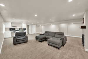 Living area with recessed lighting, light colored carpet, and a fireplace