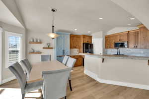 Dining area with vaulted ceiling, light wood finished floors, and recessed lighting