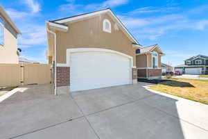 View of front facade featuring brick siding, a gate, driveway, and stucco siding