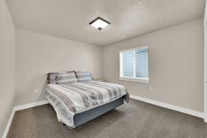 Bedroom featuring dark colored carpet and a textured ceiling
