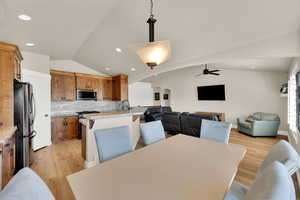 Dining space featuring arched walkways, light wood-type flooring, lofted ceiling, a ceiling fan, and recessed lighting