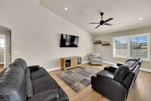 Living room featuring arched walkways, light wood-style floors, vaulted ceiling, ceiling fan, and recessed lighting