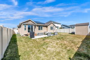 Rear view of house featuring a shed, a patio, stucco siding, solar panels, and a fenced backyard