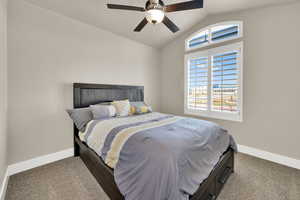 Carpeted bedroom featuring lofted ceiling and a ceiling fan