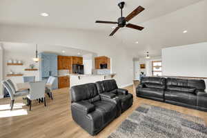 Living room featuring light wood-style flooring, ceiling fan, recessed lighting, and lofted ceiling