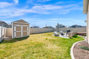 Fenced backyard featuring a patio area, a shed, and a residential view