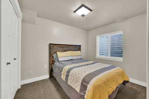 Carpeted bedroom featuring a textured ceiling and a closet