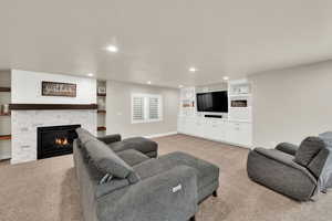 Living room featuring recessed lighting, a fireplace, and light colored carpet