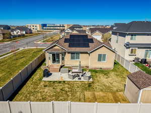 Rear view of house with outdoor furniture, roof mounted solar panels, a shingled roof, a residential view, and a fenced backyard