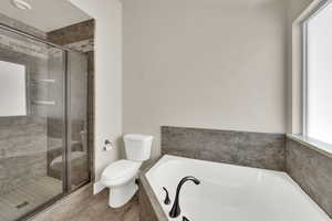 Full bathroom featuring a bath, a stall shower, and wood finished floors