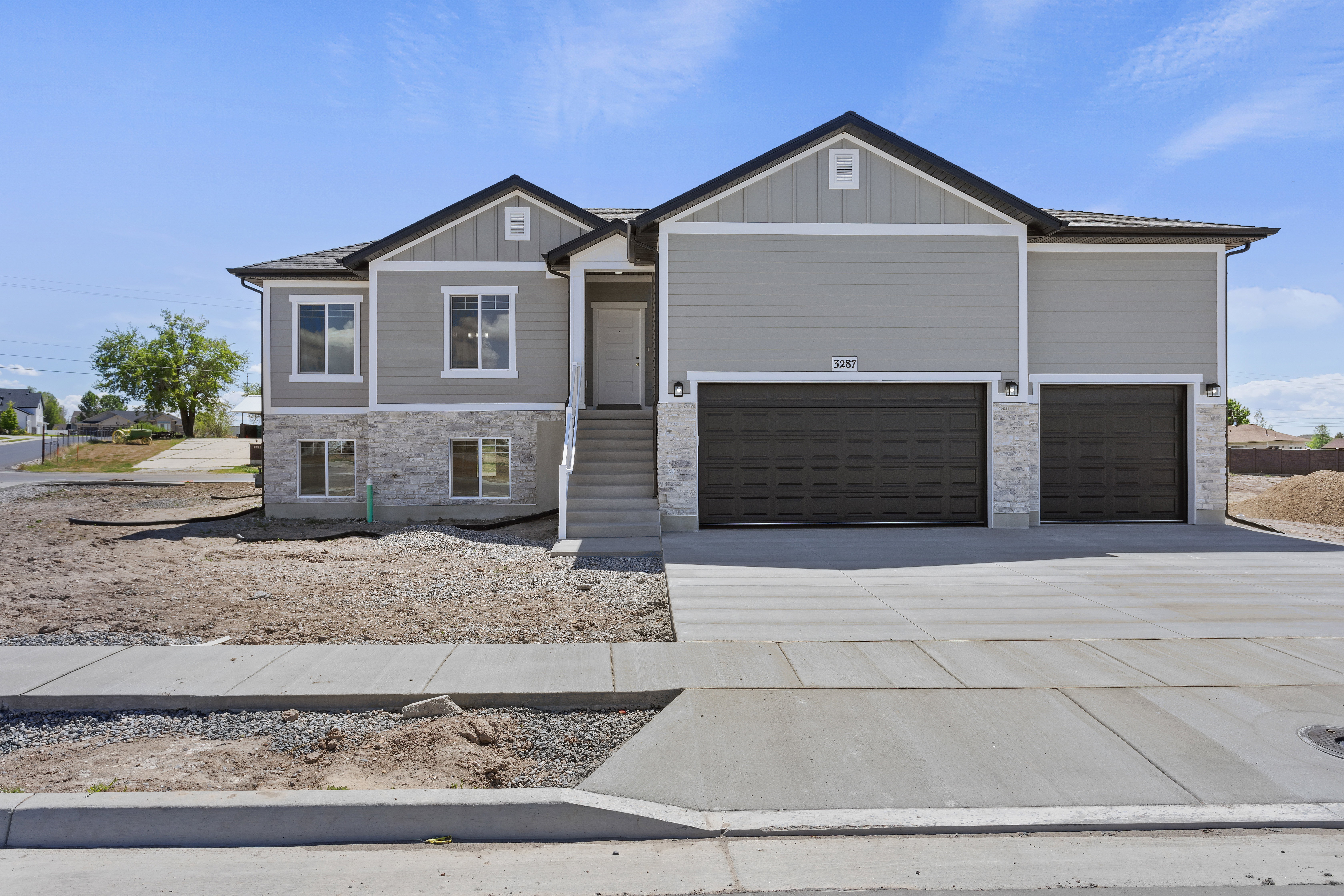 Craftsman-style home featuring concrete driveway, stone siding, board and batten siding, and an attached garage