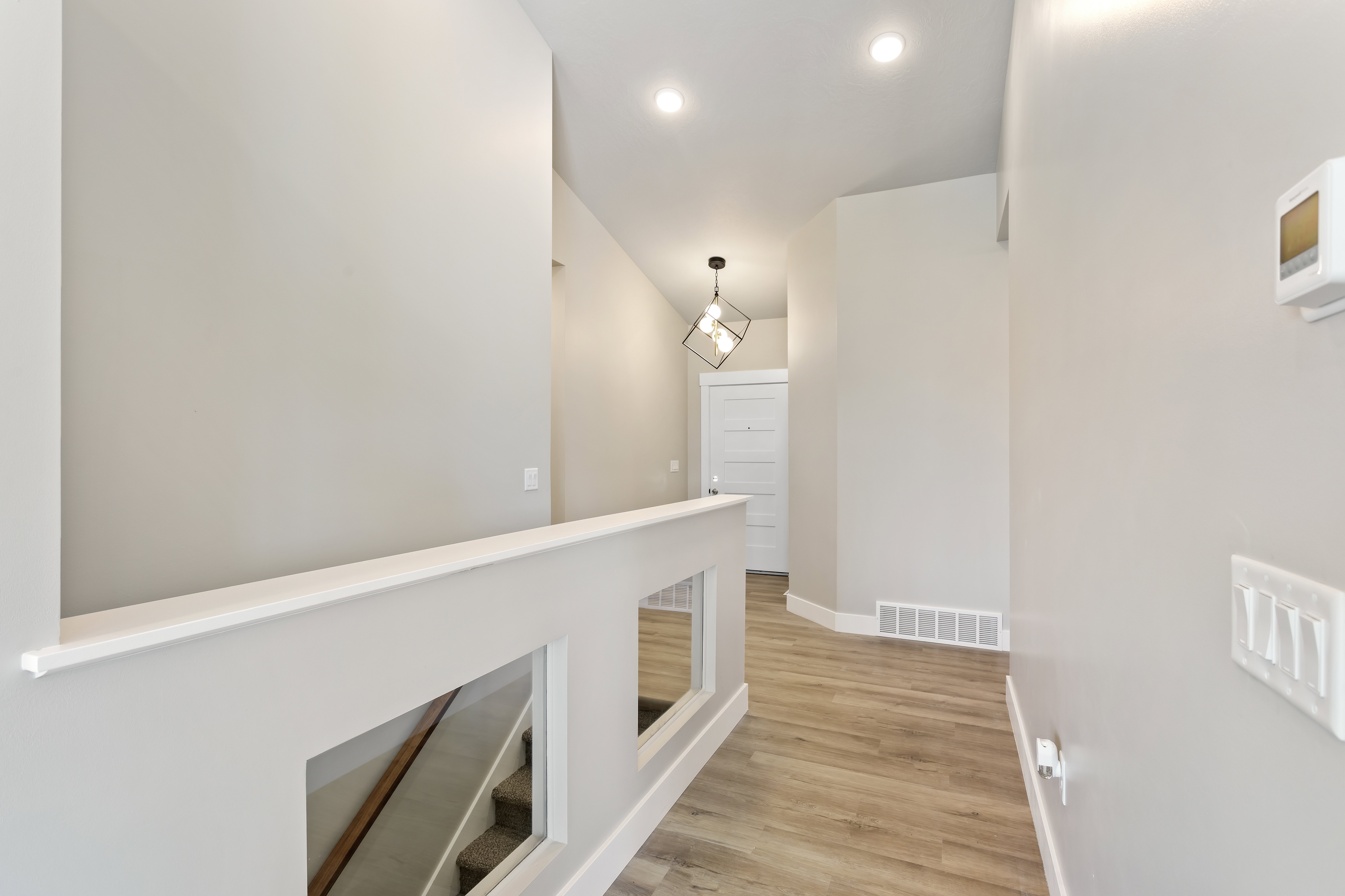 Corridor with light wood-type flooring and an upstairs landing