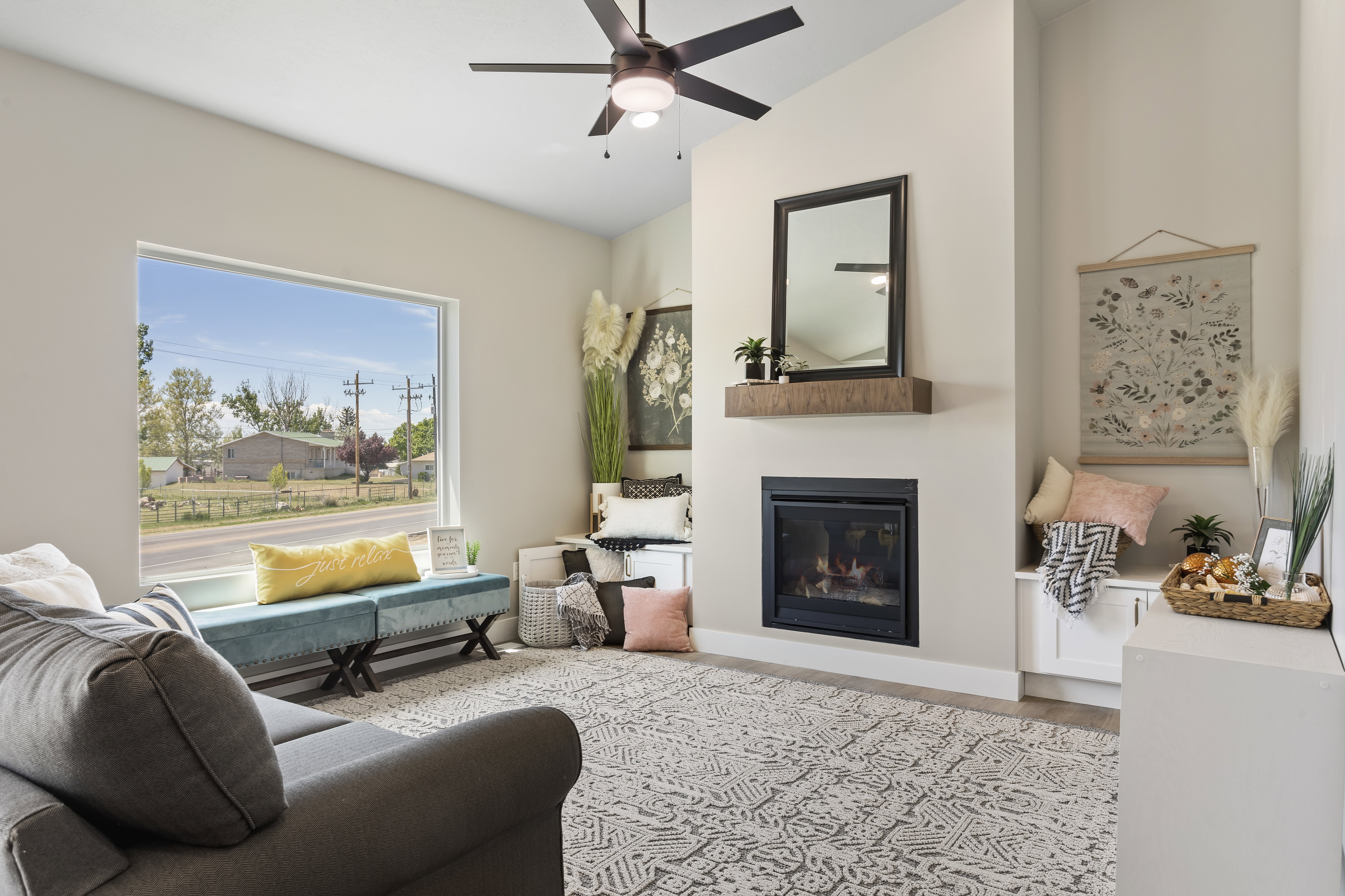 Living room featuring a glass covered fireplace, wood finished floors, a ceiling fan, and vaulted ceiling