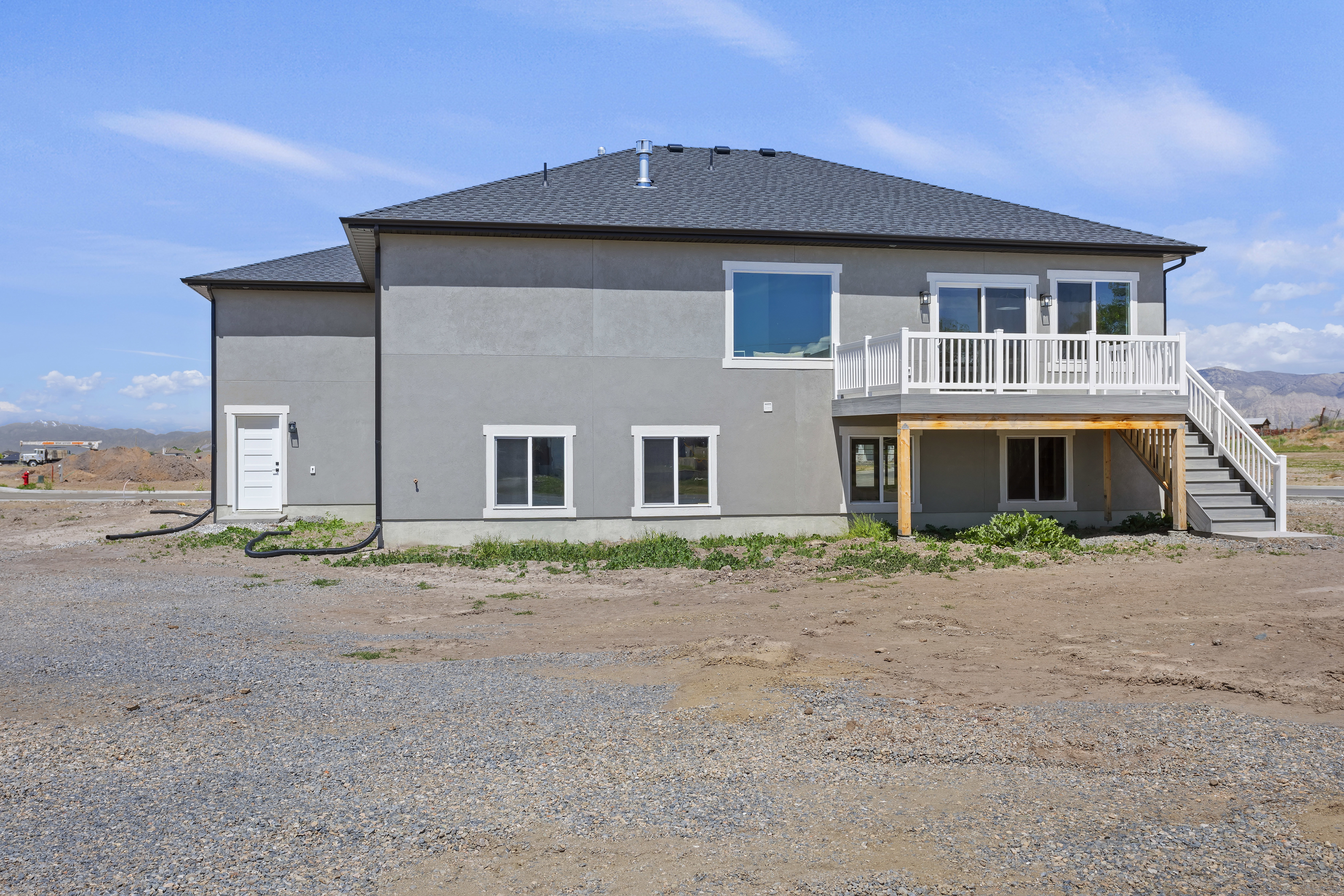 Back of property featuring a deck, a shingled roof, and stucco siding