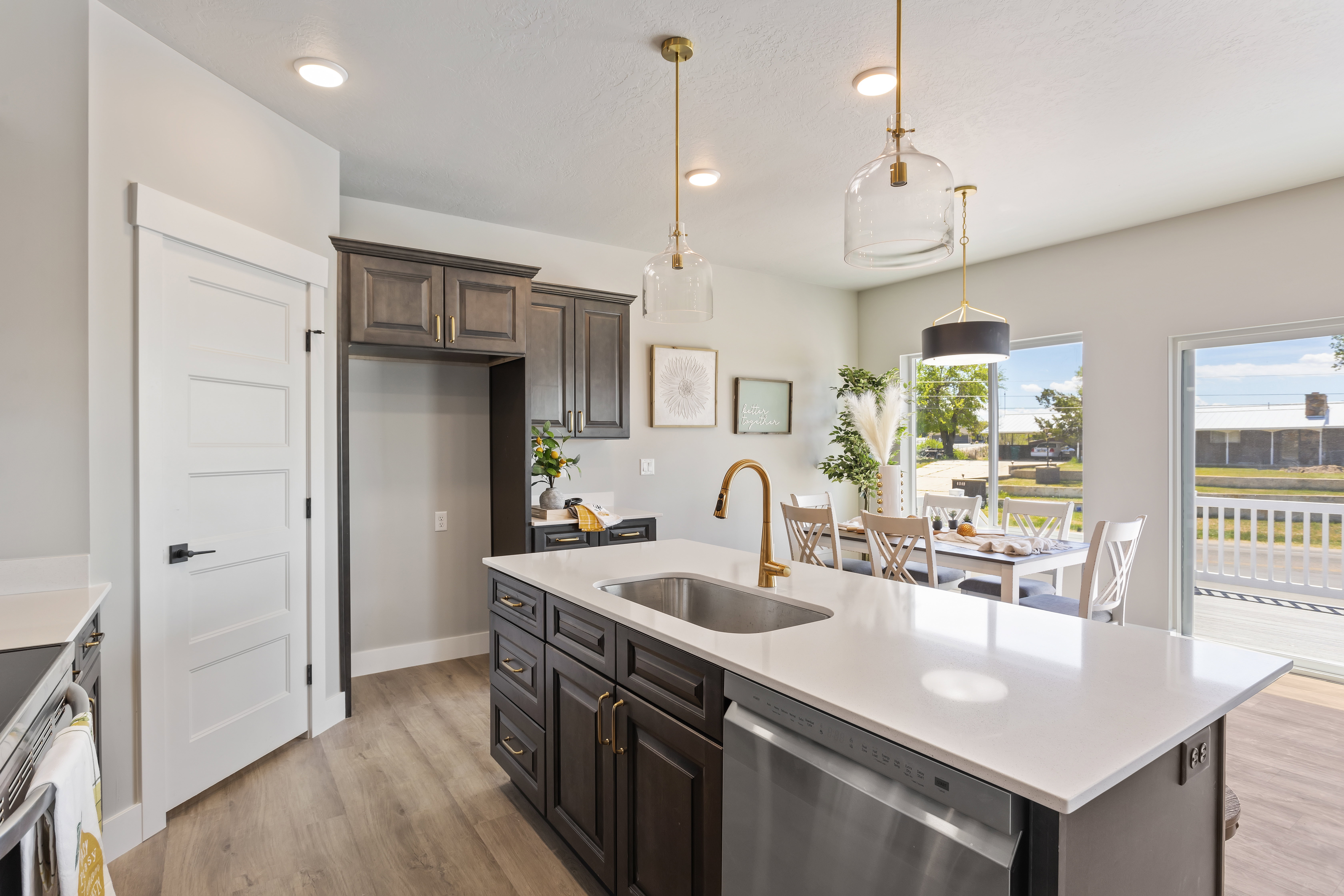 Kitchen featuring stainless steel appliances, light wood-type flooring, an island with sink, and dark wood finish cabinetry